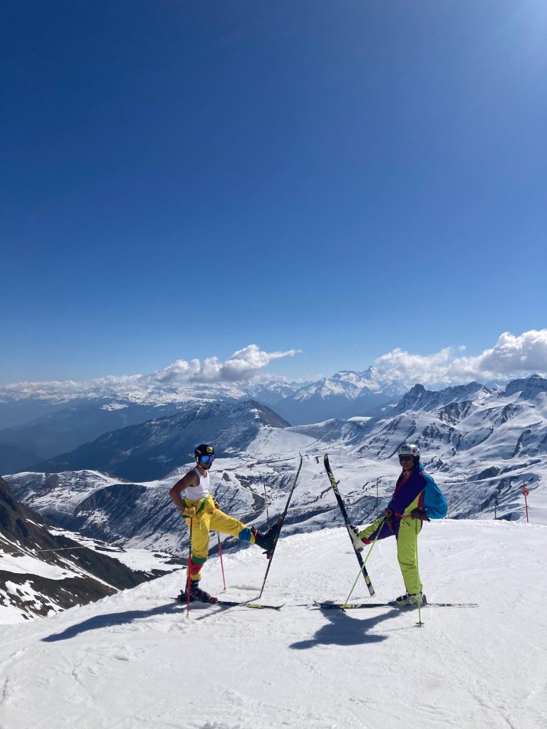 Skieurs au sommet face aux Alpes enneigées